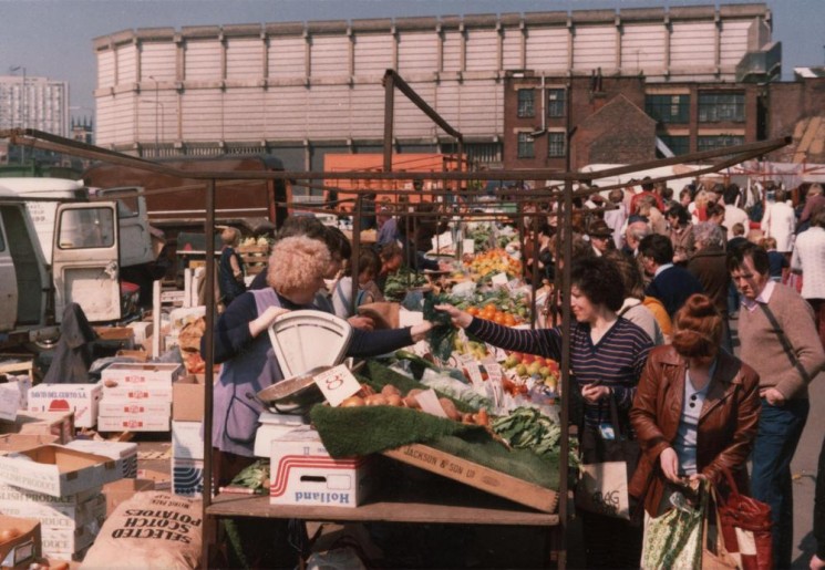 Fruit & veg stall at Moorfoot market. Moore St sub-station and Hallamshire Hospital in the background, May 1980 | Photo: Tony Allwright